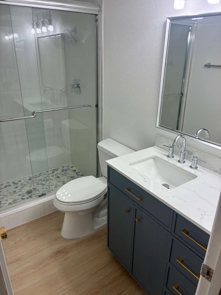 Bathroom remodel with glass shower blue vanity and gold hardware in North Port FL
