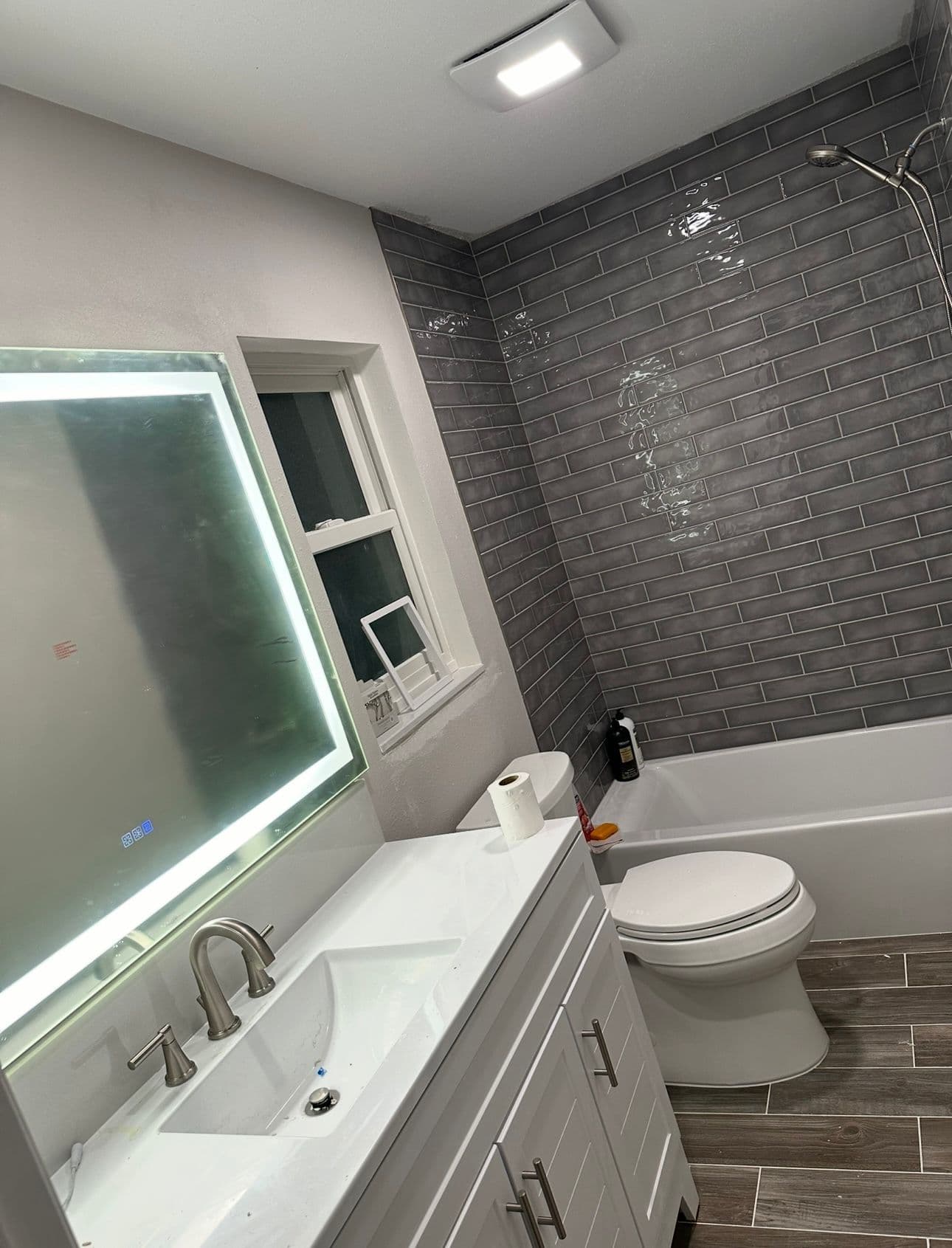 Bathroom remodel with gray tile white vanity and LED mirror in North Port FL
