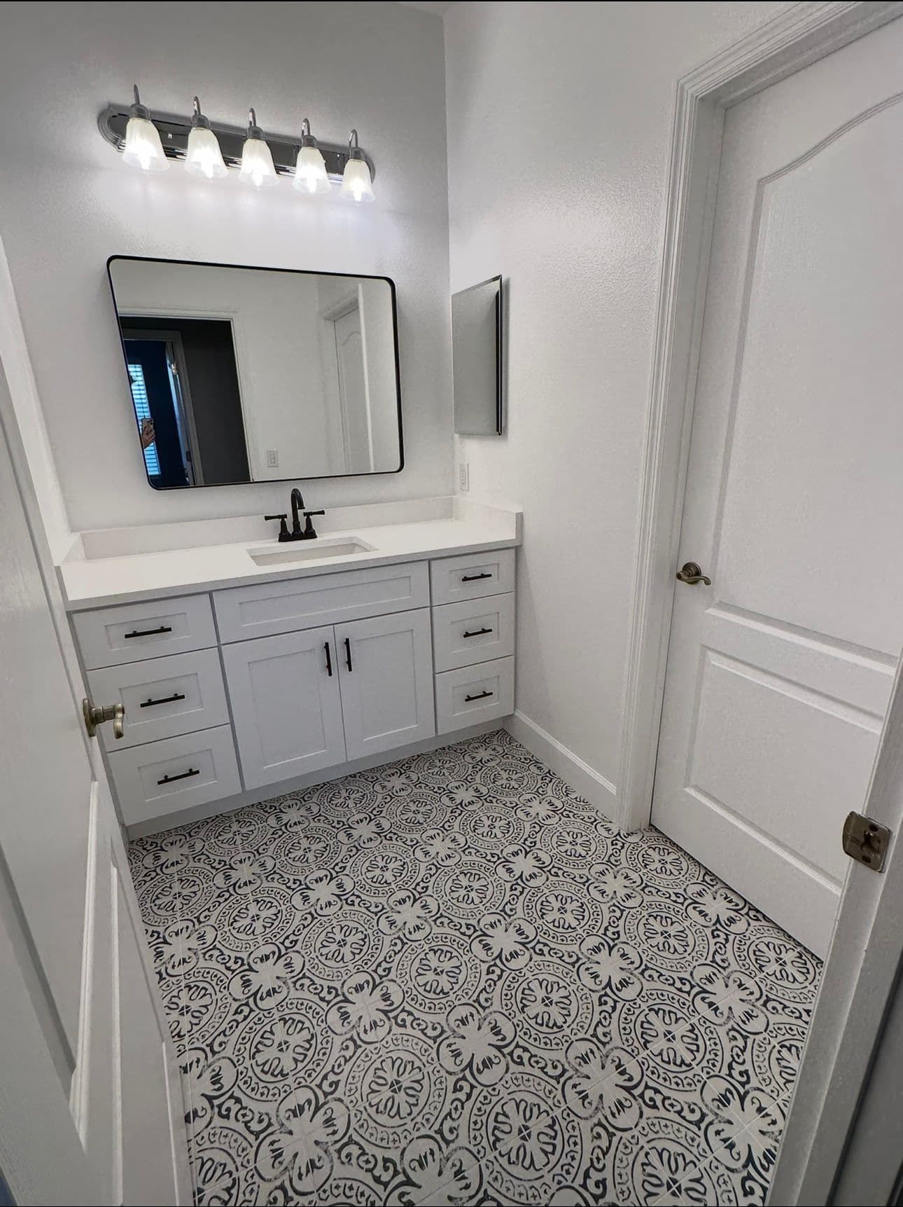 Bathroom remodel with white vanity and black and white patterned tile floor in North Port FL