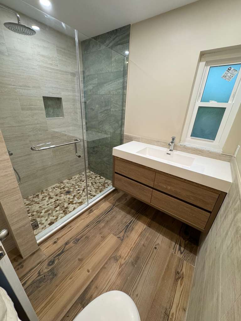 Bathroom remodel with wood floors stone shower and floating vanity in North Port FL