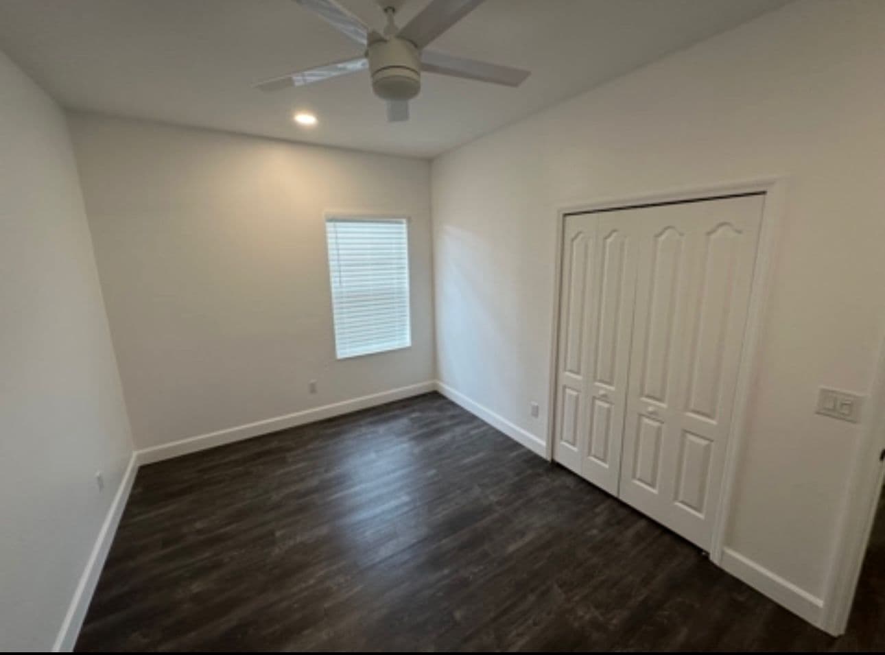Bedroom remodel with dark floors white walls and closet in North Port FL