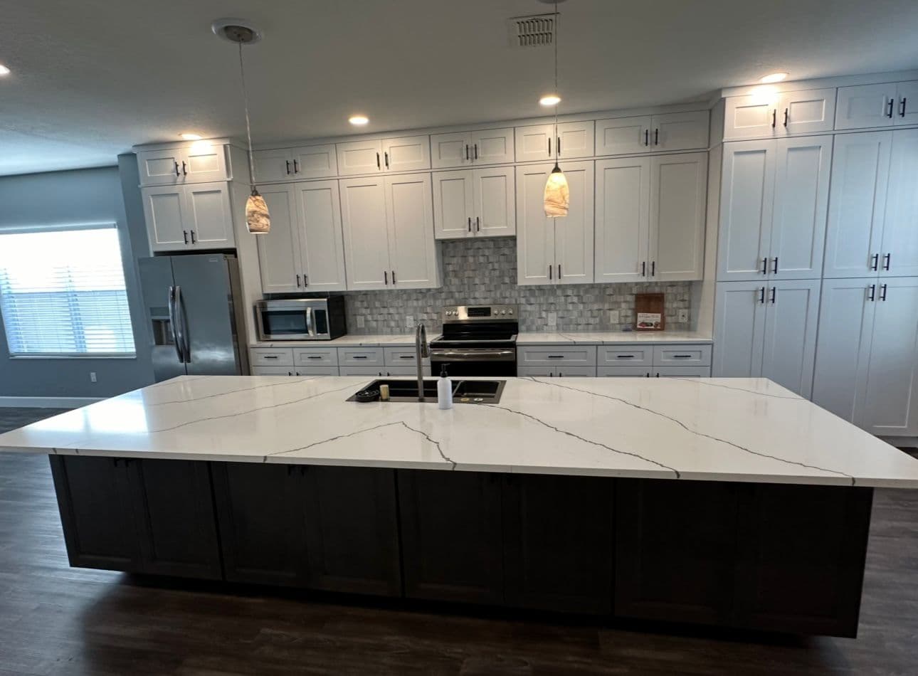 Kitchen remodel with white cabinets dark island and marble countertop in North Port FL