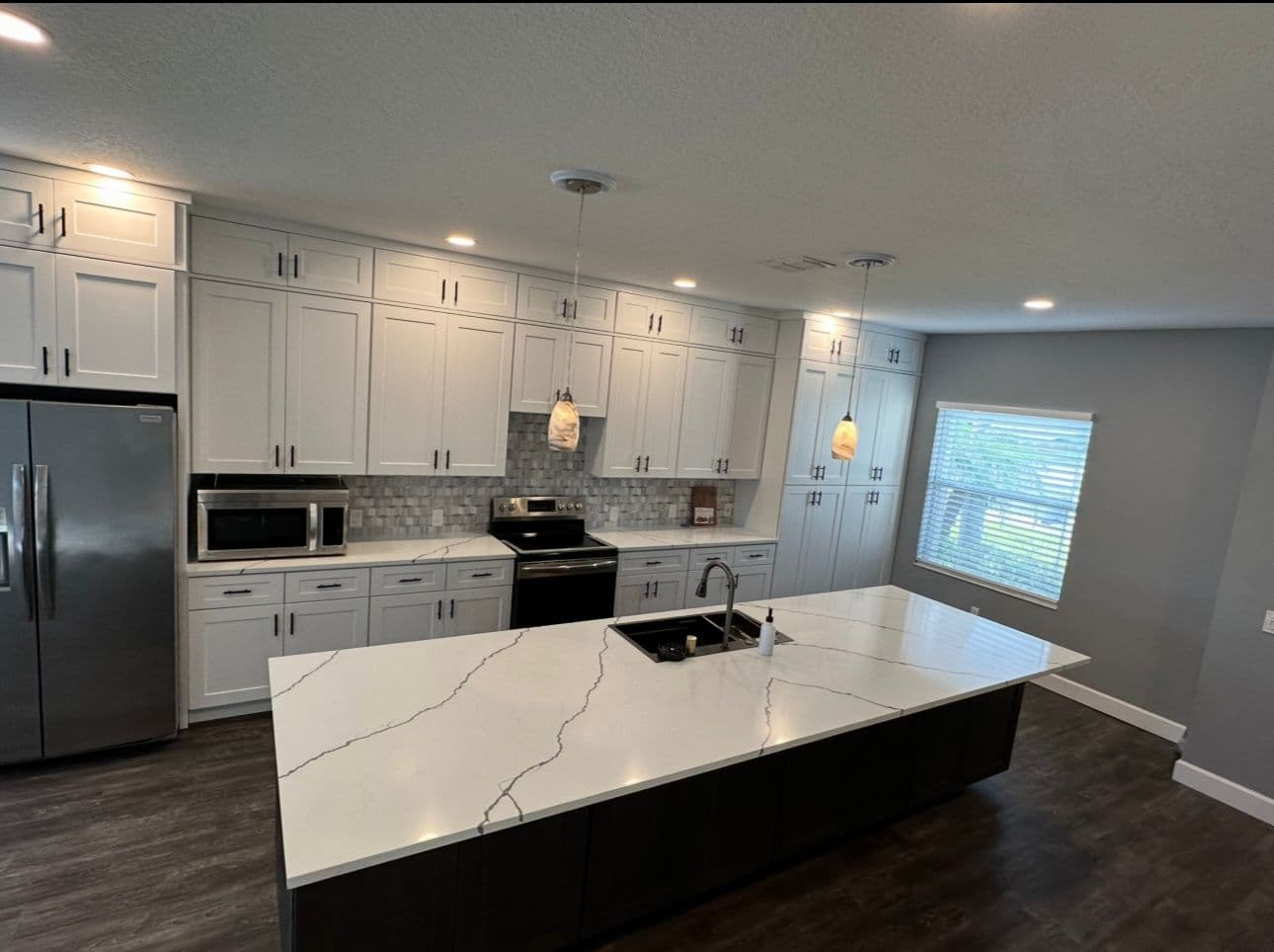 Kitchen remodel with white cabinets marble countertop and center island in North Port FL
