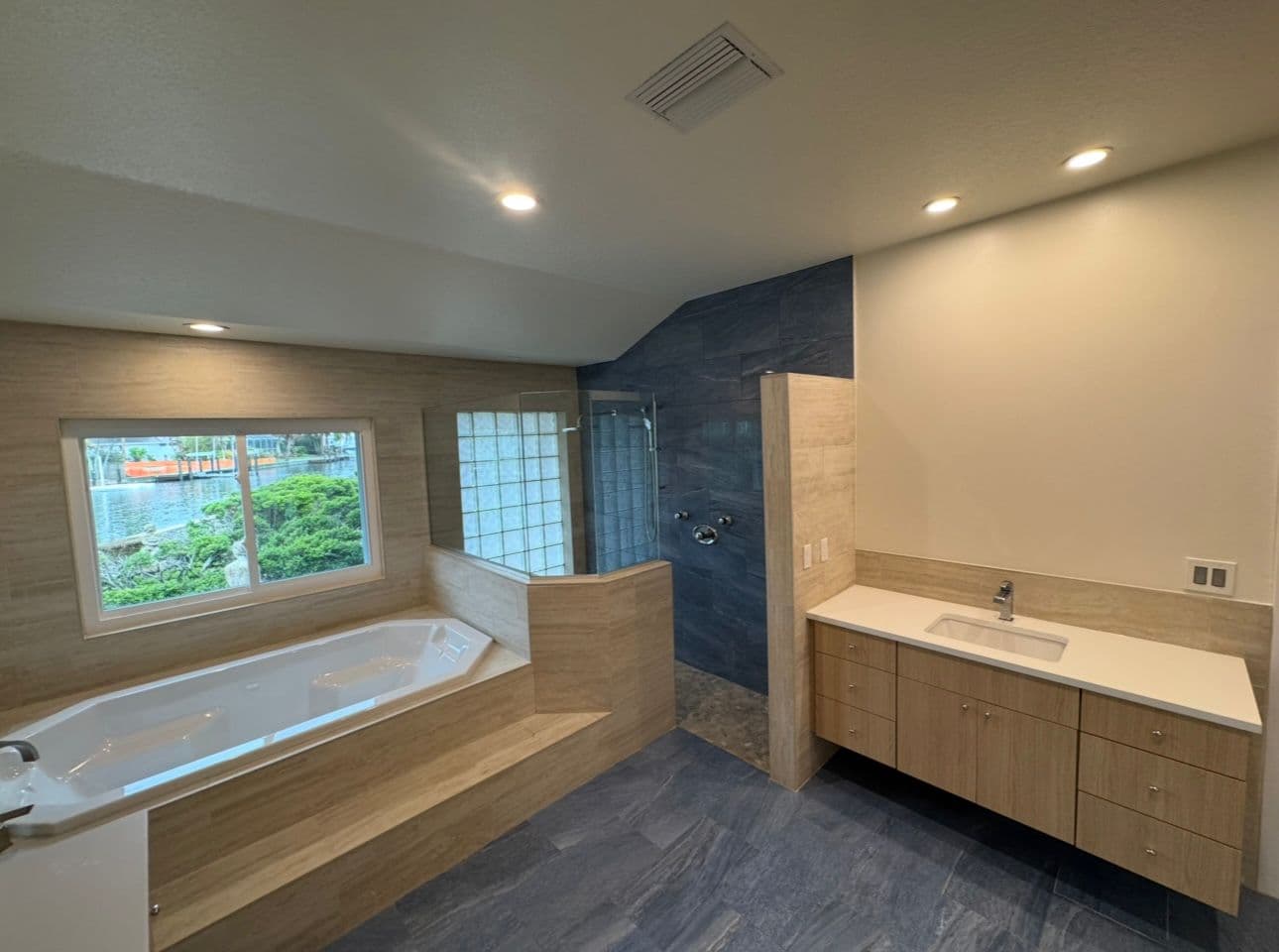 Modern bathroom remodel with blue tile large tub and wood vanity in North Port FL