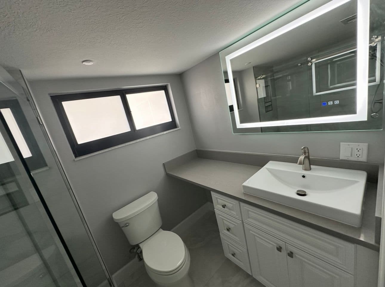 Modern bathroom vanity with LED mirror and gray countertop in North Port FL