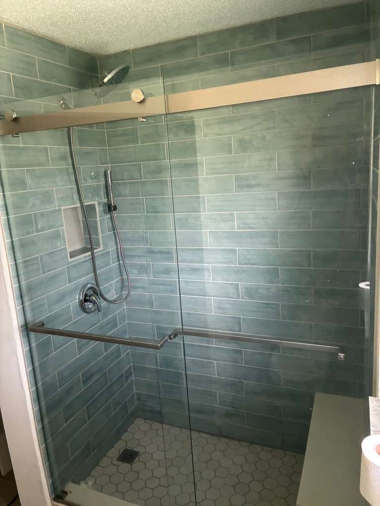Shower remodel with blue green tile glass door and hexagon floor in North Port FL