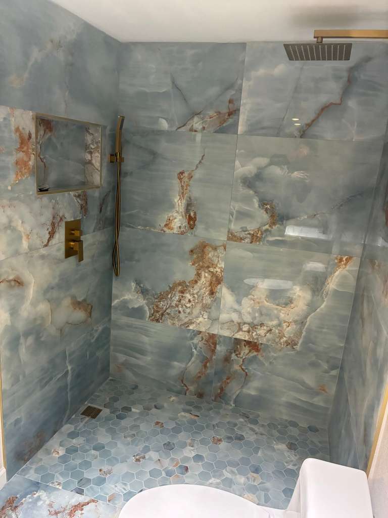 Shower remodel with blue onyx tile hexagon floor and gold fixtures in North Port FL