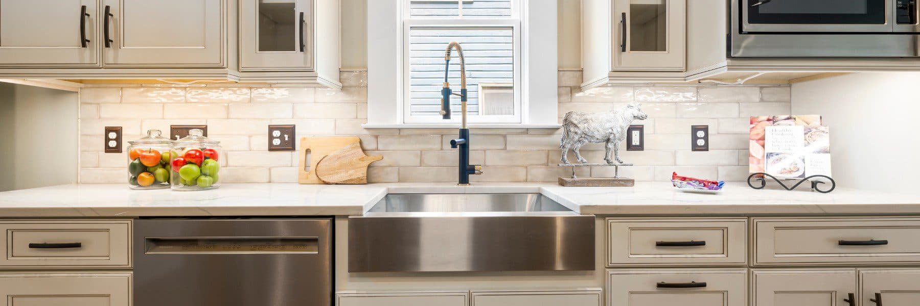 Kitchen detail with farmhouse sink cream cabinets and subway tile backsplash